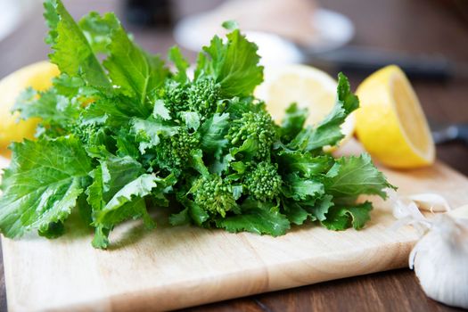Broccoli rabe on a cutting board with lemons in the background