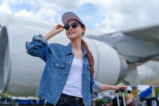 Portrait of an Asian woman holding a suitcase for a trip after getting off an economy class plane, concept vacation, tourism.