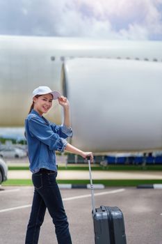 Portrait of an Asian woman holding a suitcase for a trip after getting off an economy class plane, concept vacation, tourism.