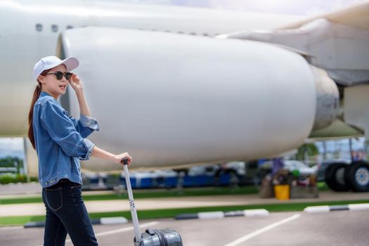 Portrait of an Asian woman holding a suitcase for a trip after getting off an economy class plane, concept vacation, tourism.