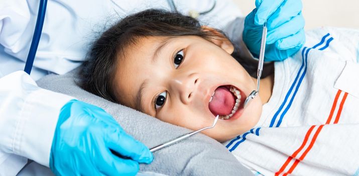 Dental kid health examination. Asian dentist making examination procedure for cute little girl open mouth, Doctor examines oral cavity of little child uses mouth mirror to checking teeth cavity