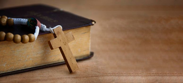 Holy Bible and Rosary on a wooden table with customizable space to add ideas or text. Copy space and Christianity concept.