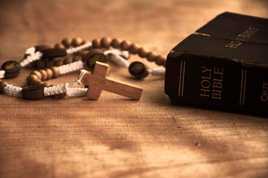Holy Bible and Rosary on a wooden table with customizable space to add ideas or text. Copy space and Christianity concept.