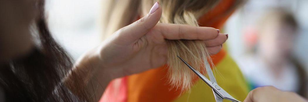 Close-up of woman holding lock of hair and cutting with scissors equipment. Female help with hairstyle her girlfriend at home. Lgbt, beauty, image concept