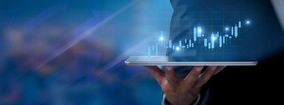 Hand of businessman holding tablet analysis stock market graph growth and increase of chart positive indicators. Hand holding tablet show stock chart on light gray background. copy space banner