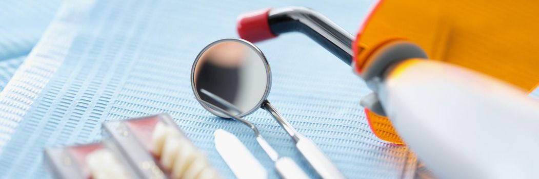 Close-up of set of dentist medical tools for cure people teeth. Whitening instrument, tiny mirror, teeth sample on surface. Stomatology cabinet concept