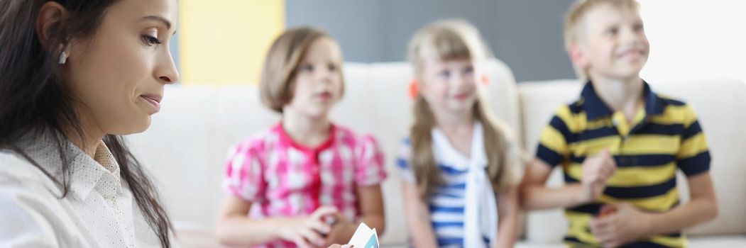 Portrait of group of kids spend time in kindergarten with female teacher. Mother entertain children with games on holiday. Childhood, fun, family concept