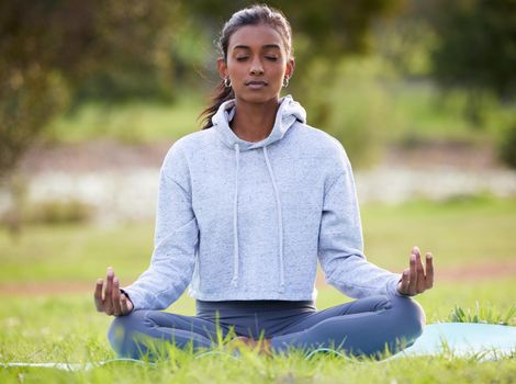 a young woman meditating in the park.