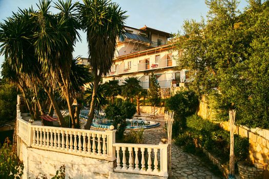 A small hotel with a swimming pool and palm trees in Albania. High quality photo