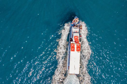 Ferry boat with tourists on the move on floats on turquoise water. Drone view.