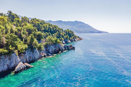 Picturesque sea Adriatic coast of Montenegro. Turquoise Mediteran sea and rocky shore with evergreen coniferous trees. Wonderful summer landscape. Drone.