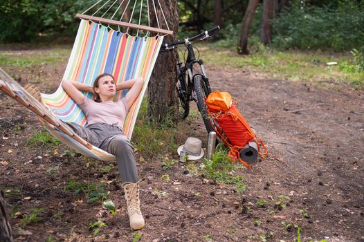 Caucasian woman lies in a hammock in a pine forest.