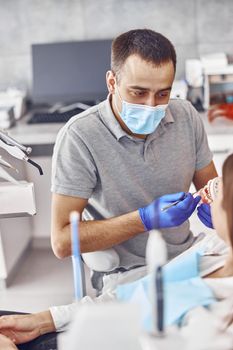 Professional doctor is choosing a colour of teeth in modern dental clinic