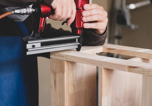 Entrepreneur Woodwork holding a Tacker to assemble the wood pieces as the customer ordered