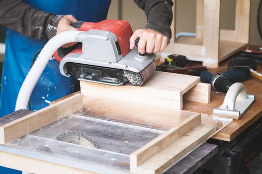 Woodworking entrepreneurs use sandpaper finishing machines to assemble and build wooden tables for their clients