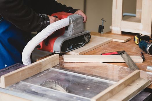 Woodworking entrepreneurs use sandpaper finishing machines to assemble and build wooden tables for their clients