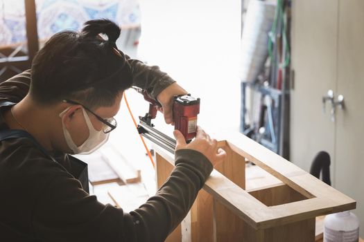 Entrepreneur Woodwork holding a Tacker to assemble the wood pieces as the customer ordered