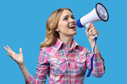 Excited young woman talking into megaphone on color background. Holiday sales.