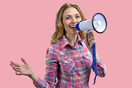 Happy young woman in stylish shirt talking into megaphone with a smile. Pretty girl talks into megaphone on color background.