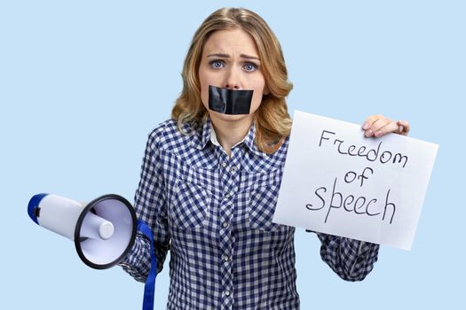 Confused young woman holding card with inscription Freedom of speech on color background. Censorship in expression of opinion.