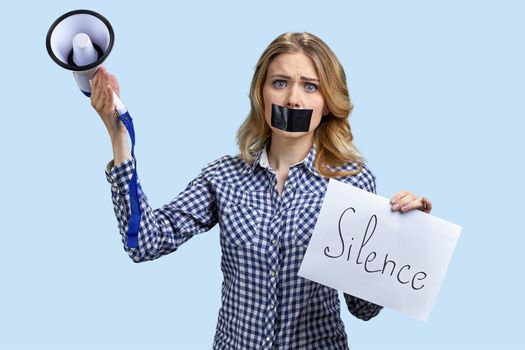 Woman protester with taped mouth holding banner with inscription Silence. Free speech concept.