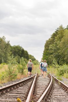 a group of tourists travelers in summer clothes walk along the old railway tracks travel, hiking in nature. High quality photo