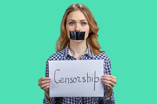 Young caucasian woman with taped mouth holding banner with inscription Censorship. Young beautiful woman with black tape on her mouth.
