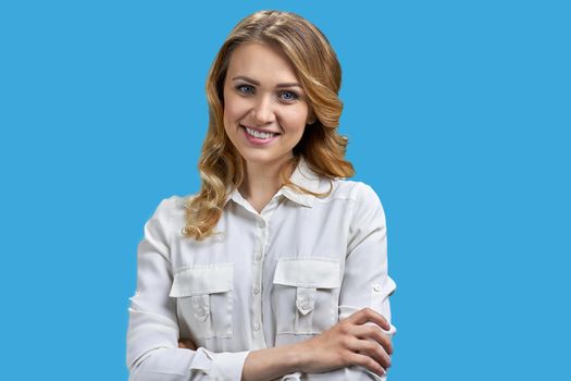 Young charming office lady posing at camera on blue background. Pretty woman in white blouse looking at camera.