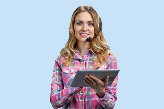 Female customer support operator with tablet pc looking at camera. Call center agent working on digital tablet against blue background.