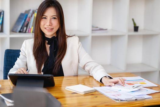 Portrait of a business woman using a tablet computer and calculator for data analysis, marketing, accounting.