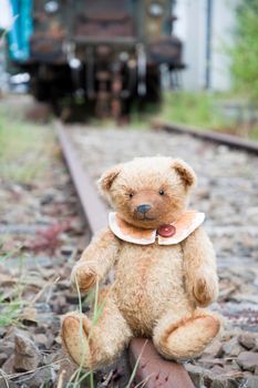 a cute brown teddy bear sits alone on empty mini-rails and looks into the distance, do-it-yourself toy. High quality photo