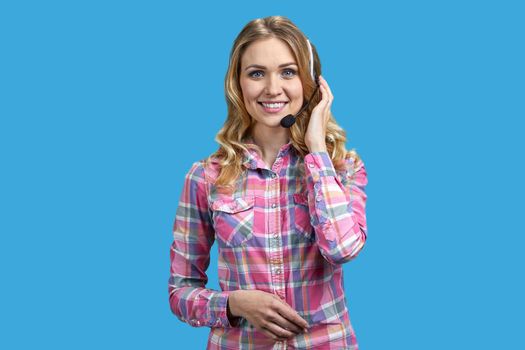 Young pretty woman with headset talking to someone online against color background. Customer service operator at work.