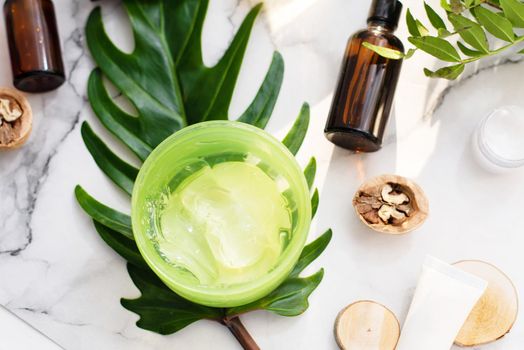 A beautiful composition with oil, aloe, soap and nuts. Bottles with spa cosmetic products on a palm leaf background, top view. Beauty salon procedures concept.