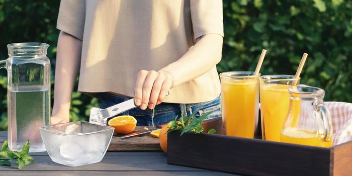 Girl cooking summer orange cocktail with mint and ice cubes outdoors, selective focus.