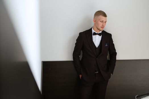 portrait of the groom in a brown three-piece suit with a bow tie on the wedding day