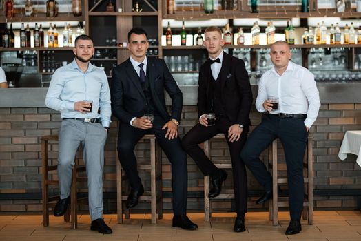 groom in a brown suit and his friends at the bar