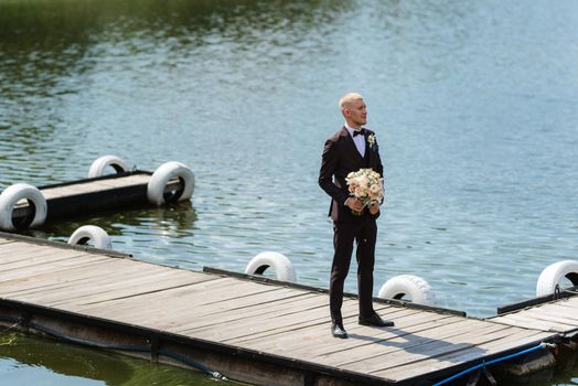 portrait of the groom in a brown three-piece suit with a bow tie on the wedding day