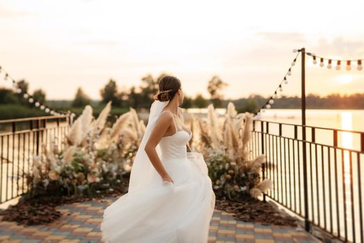 bride against the background of a yellow sunset on a pier near the river