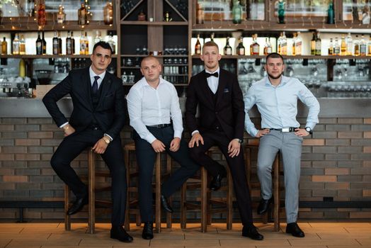 groom in a brown suit and his friends at the bar