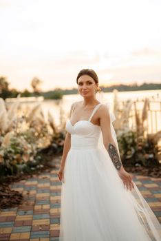 bride against the background of a yellow sunset on a pier near the river