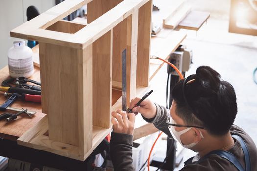 A carpenter measures the planks to assemble the parts, and build a wooden table for the customer