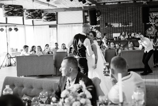 the first wedding dance of the bride and groom inside the restaurant hall in sunset light