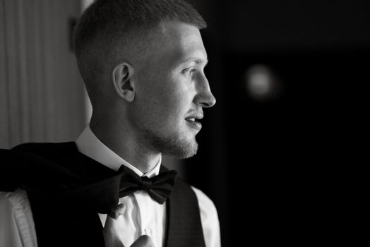 portrait of the groom in a brown three-piece suit with a bow tie on the wedding day