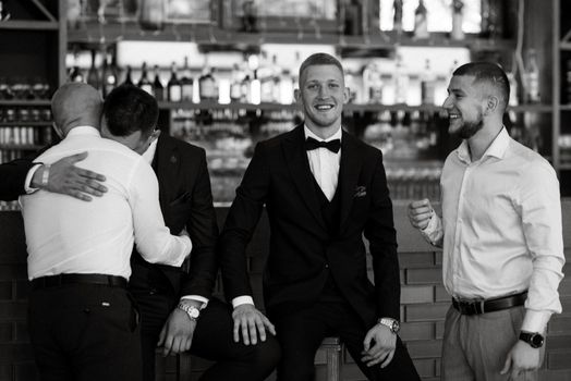 groom in a brown suit and his friends at the bar