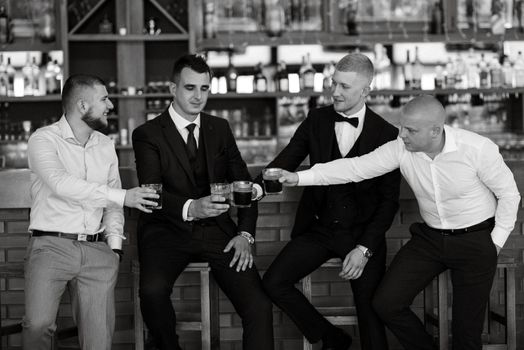 groom in a brown suit and his friends at the bar