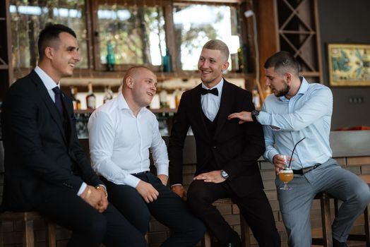 groom in a brown suit and his friends at the bar