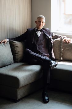 portrait of the groom in a brown three-piece suit with a bow tie on the wedding day