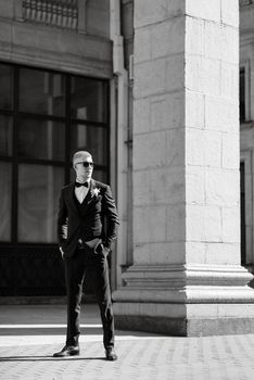 portrait of the groom in a brown three-piece suit with a bow tie on the wedding day