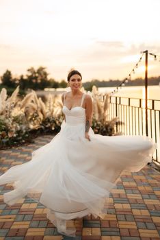 bride against the background of a yellow sunset on a pier near the river