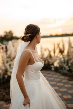 bride against the background of a yellow sunset on a pier near the river